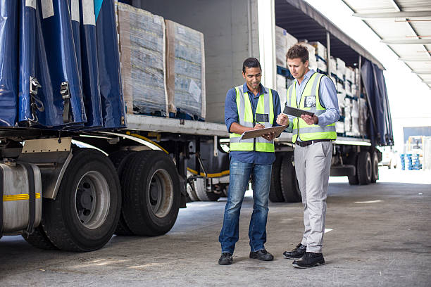 Workers loading and inspecting  a lorry at a large warehouse